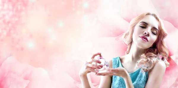 Belle femme avec bouteille de parfum en fleurs sur fond rose — Photo
