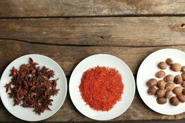 Different spices on plates, on old wooden table — Stock Photo, Image