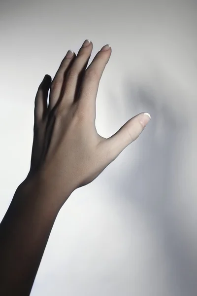 Weibliche Hand und blauer Schatten auf hellem, buntem Hintergrund — Stockfoto