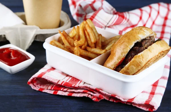 Νόστιμο burger και τηγανητές πατάτες στο πιάτο, σε ξύλινο τραπέζι φόντο. Έννοια ανθυγιεινών τροφίμων — Φωτογραφία Αρχείου