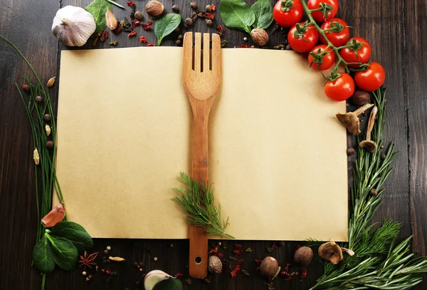 Libro de recetas abierto con hierbas frescas, tomates y especias sobre fondo de madera — Foto de Stock