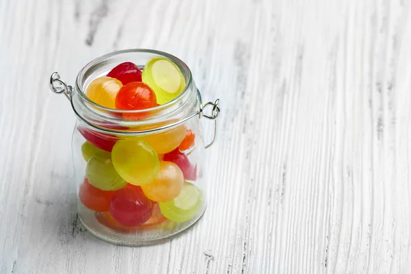 Bonbons colorés en pot sur fond en bois — Photo