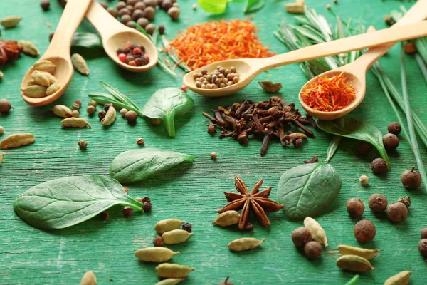 Cuillères en bois avec herbes fraîches et épices sur fond en bois — Photo