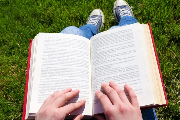 Jovem com livro sentado na grama verde ao ar livre — Fotografia de Stock
