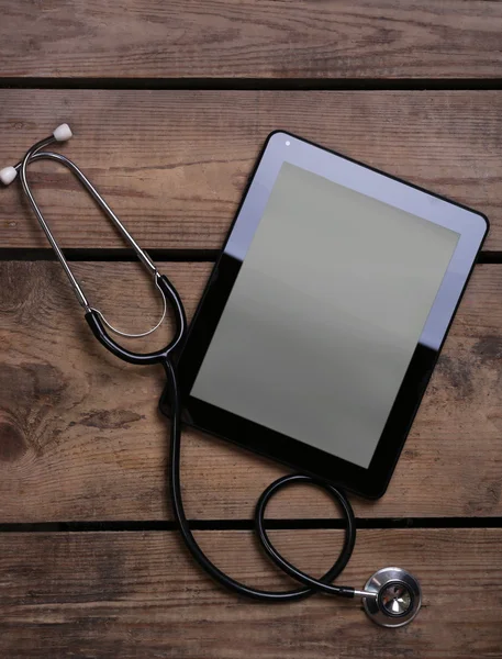 Tableta médica con estetoscopio sobre fondo de madera —  Fotos de Stock