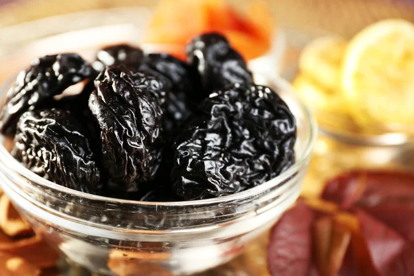 Pile of prunes in glass saucers with grape leaves, closeup — Stock Photo, Image