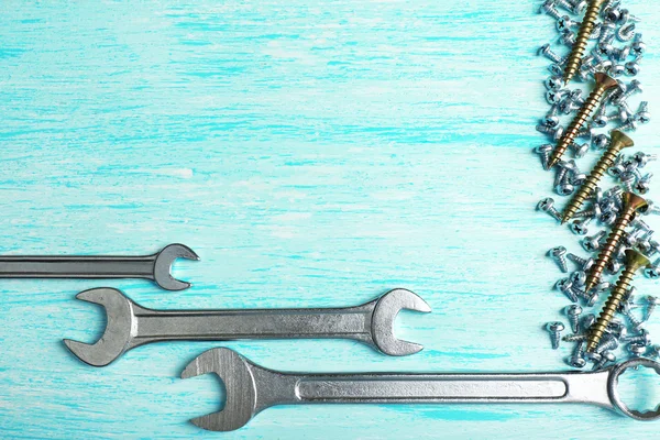 Rahmen mit Schraubenmuttern und Schlüsseln, auf farbigem Holzhintergrund — Stockfoto