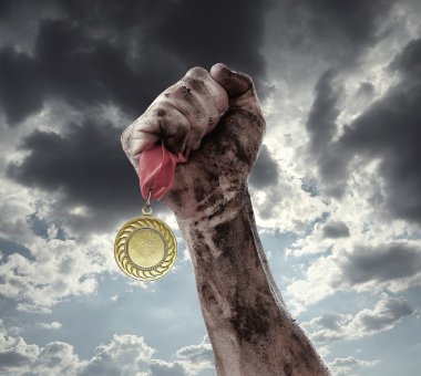 Golden medal in hand on sky background clipart