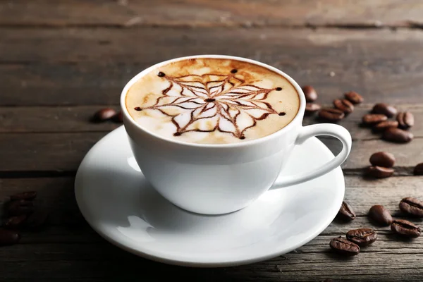 Cup of latte art coffee with grains on wooden background — Stock Photo, Image