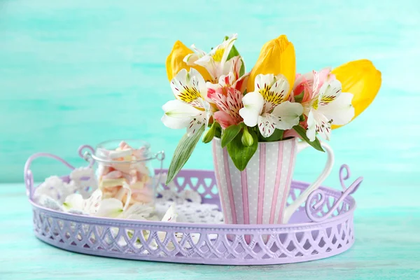 Schöne Blumen in Tasse, auf farbigem Holzhintergrund — Stockfoto