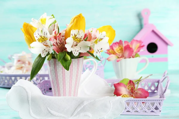 Schöne Blumen in Tasse, auf farbigem Holzhintergrund — Stockfoto