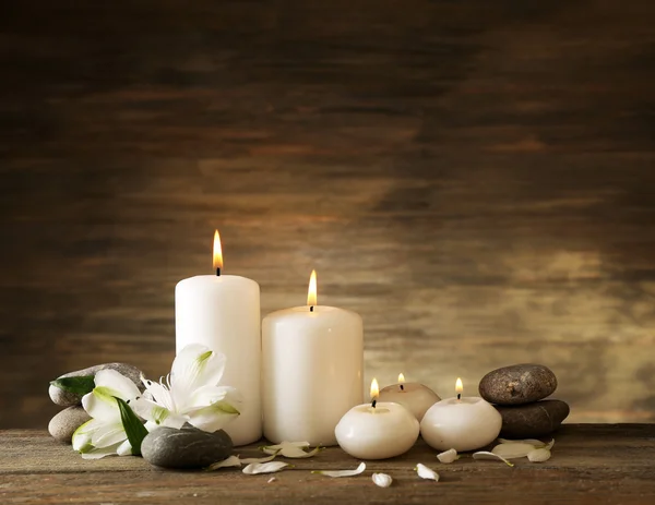 Красива композиція зі свічками та спа-камінцями на дерев'яному фоні — стокове фото