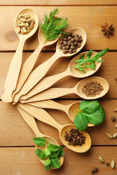 Cucchiai di legno con erbe fresche e spezie su sfondo di legno — Foto Stock