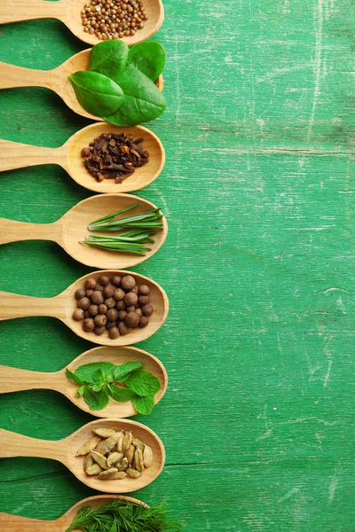 Cucchiai di legno con erbe fresche e spezie su sfondo di legno a colori — Foto Stock