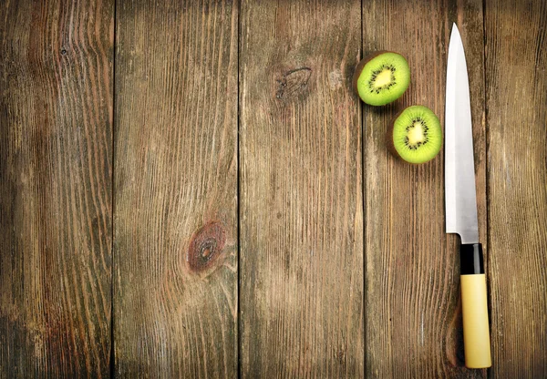 Halves of kiwi with knife on wooden background — Stock Photo, Image