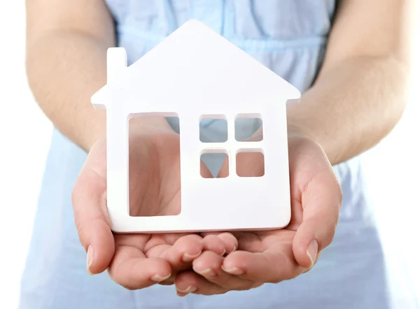 Mani femminili con piccolo modello di casa isolato su bianco — Foto Stock