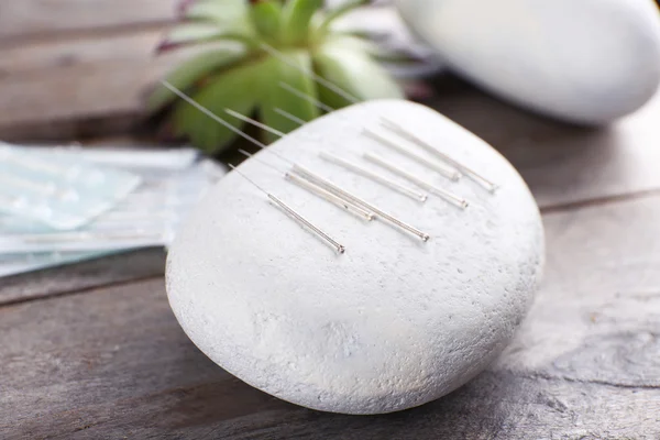 Nål för akupunktur på spa stenar på bordet på nära håll — Stockfoto