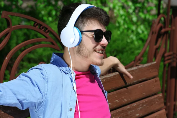 Hombre con auriculares descansando en el banco en el parque — Foto de Stock