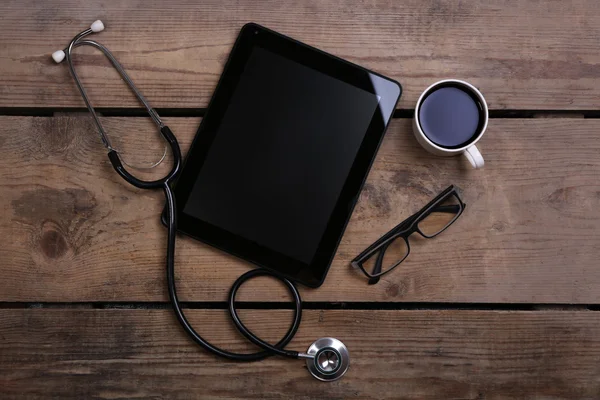 Tableta médica con estetoscopio sobre fondo de madera —  Fotos de Stock