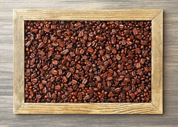 Kávová zrna v rámu na dřevěné pozadí — Stock fotografie