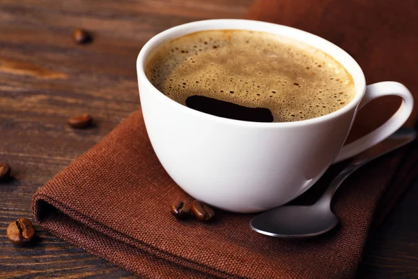 Xícara de café em guardanapo na mesa de perto — Fotografia de Stock