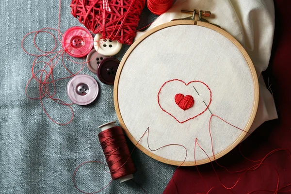 Кольцо для вышивки с холстом и красными нитками для шитья на столе — стоковое фото