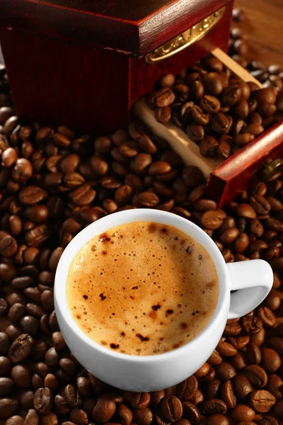 Xícara de café fresco com grãos na mesa, close-up — Fotografia de Stock