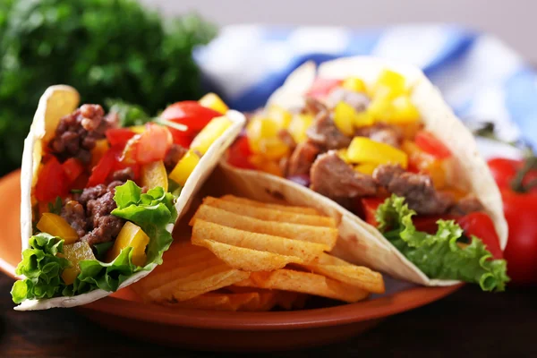 Burritos caseros de ternera con verduras, papas fritas en plato, sobre fondo de madera — Foto de Stock