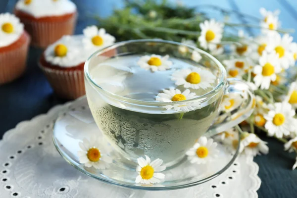 Cup of chamomile tea with chamomile flowers and tasty muffins — Stok fotoğraf