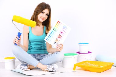 Güzel kız boyama duvar için ekipman ile katta oturan