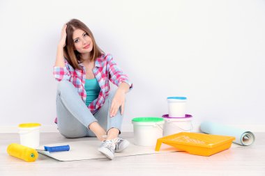 Güzel kız boyama duvar için ekipman ile katta oturan