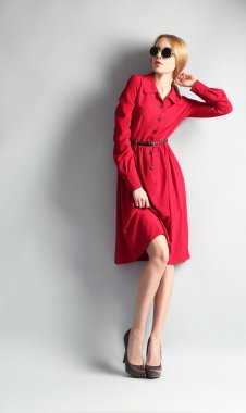 Kırmızı elbise ve gri arka plan üzerinde güneş gözlüğü ifade genç model