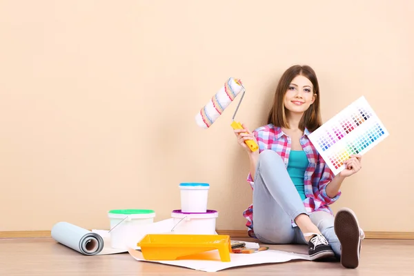 Menina bonita sentada no chão com equipamento para pintura de parede — Fotografia de Stock