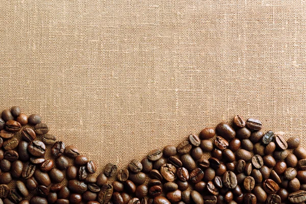 Frame of coffee beans on color sackcloth background — Stock Photo, Image