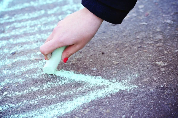 Vrouwelijke hand tekening pijl door krijt op de stoep — Stockfoto