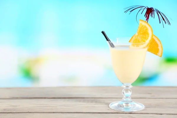 Glass of summer cocktail on wooden table on bright blurred background — Stock Photo, Image