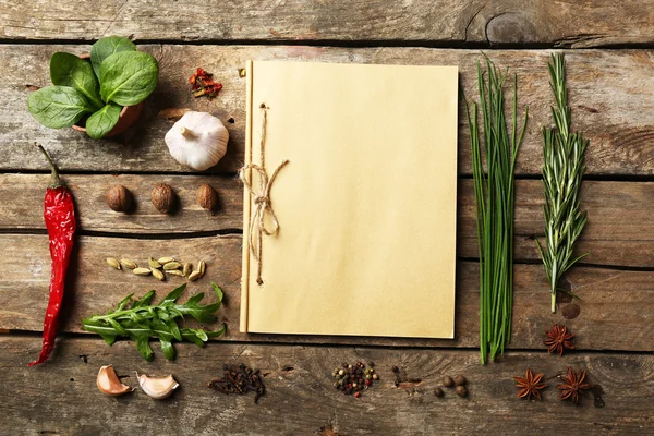 Livro de receitas aberto com ervas frescas e especiarias em fundo de madeira — Fotografia de Stock