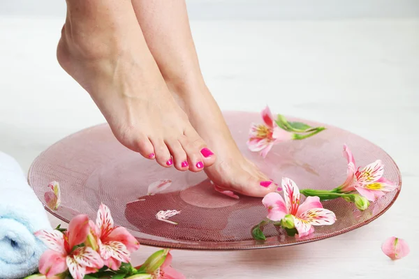 Woman washing beautiful legs in bowl, on light background. Spa procedure concept — Stock Photo, Image