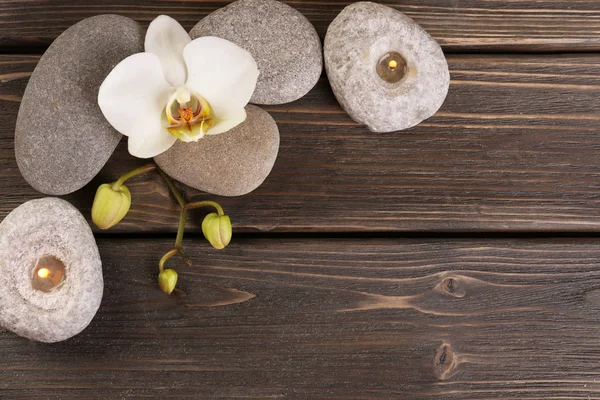 Pedras de spa e flor de orquídea em fundo de madeira — Fotografia de Stock
