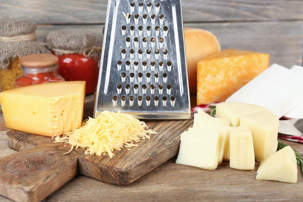 Grated cheese on wooden cutting board, closeup — Stock Photo, Image