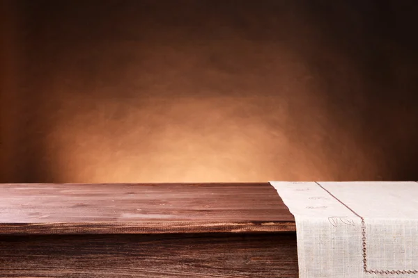 Порожній дерев'яний стіл з серветкою і коричневим фоном — стокове фото
