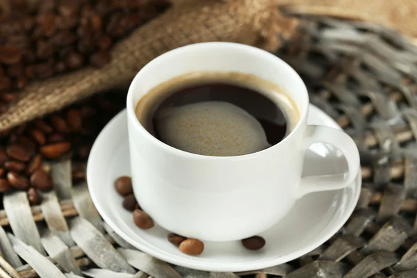 Xícara de café com grãos na mesa de perto — Fotografia de Stock