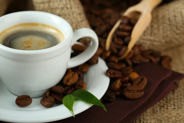 Xícara de café com grãos na mesa de perto — Fotografia de Stock