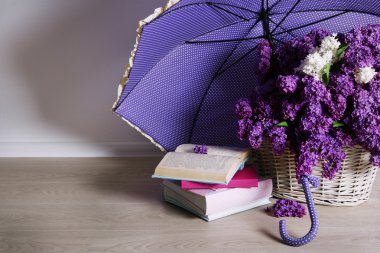 Beautiful lilac flowers with umbrella on floor in room close-up clipart