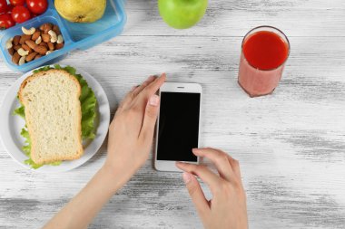 Gıda ve ahşap arka plan üzerinde eller içinde hareket eden telefon