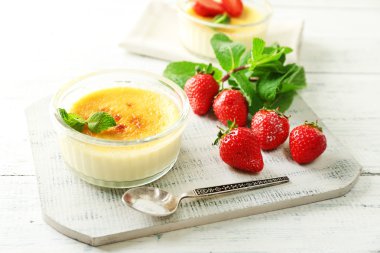 Creme brulee tatlı taze çilek ve renk ahşap zemin üzerine nane yaprakları ile
