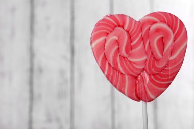 ahşap arka plan üzerinde kalp şeklinde parlak lolipop