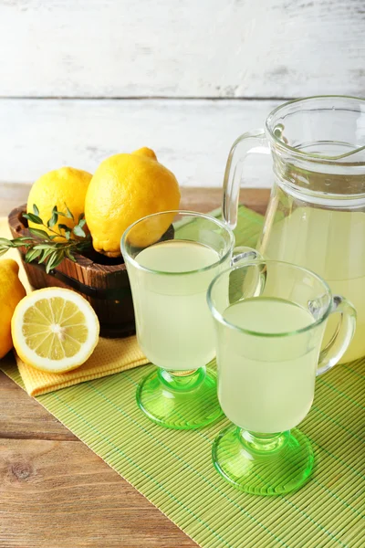 Natura morta con succo di limone e limoni affettati su fondo di legno — Foto Stock