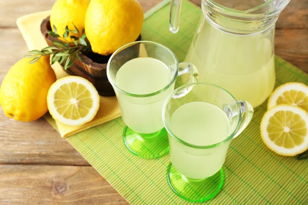 Bodegón con jugo de limón y limones en rodajas en la estera de color, primer plano —  Fotos de Stock