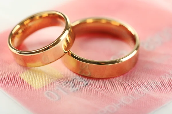 Anillos de boda dorados y tarjeta de crédito, de cerca. Concepto de matrimonio de conveniencia — Foto de Stock